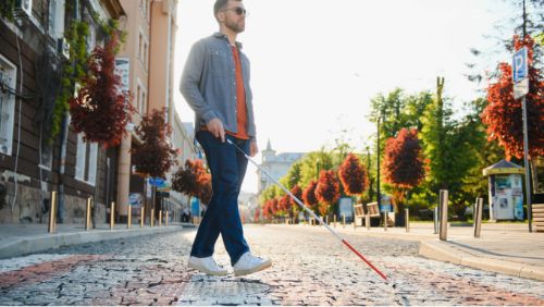 Destinos de excursiones en Mallorca: hombre explorando la ciudad con bastón para ciegos.